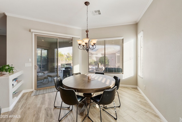 dining area with visible vents, light wood-style floors, an inviting chandelier, crown molding, and baseboards