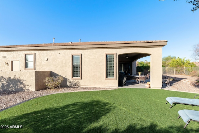 back of property with a patio, a yard, fence, and stucco siding