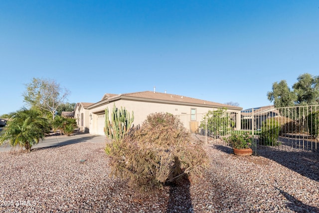 view of front of home with stucco siding, an attached garage, and fence