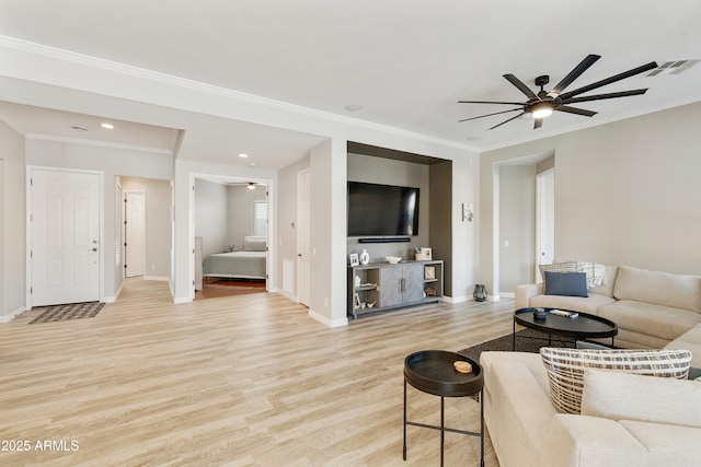 living area featuring visible vents, baseboards, crown molding, and light wood-style floors