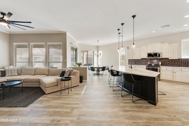 kitchen featuring visible vents, a sink, appliances with stainless steel finishes, a kitchen bar, and open floor plan