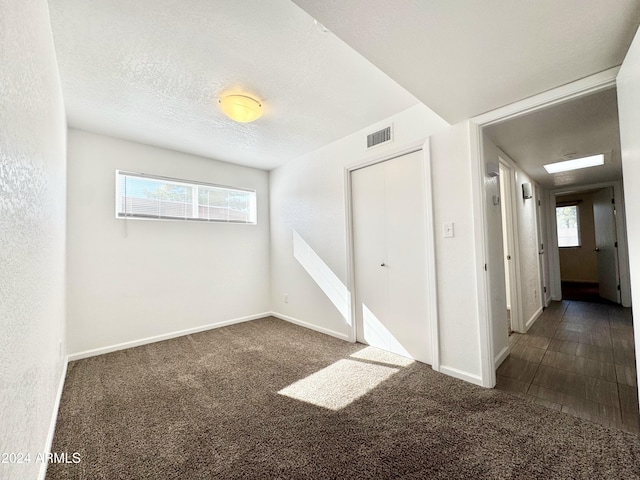 carpeted empty room featuring a healthy amount of sunlight and a textured ceiling