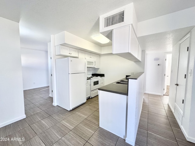 kitchen with a textured ceiling, white appliances, and white cabinetry