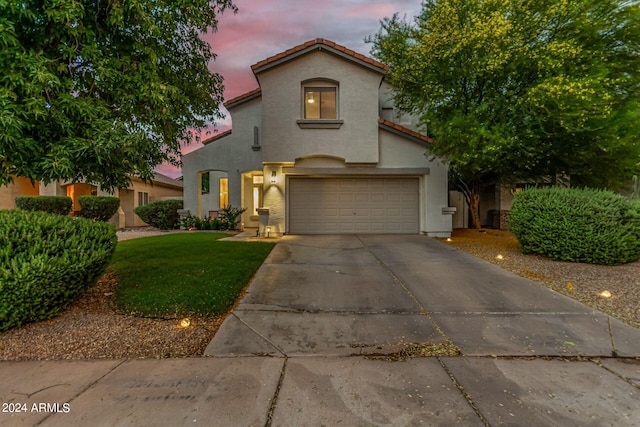 mediterranean / spanish-style home with a garage and a yard