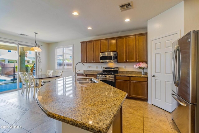 16559 W Lincoln St, Goodyear, AZ 85338 - kitchen featuring appliances with stainless steel finishes, light tile patterned floors, brown cabinetry, recessed lighting, and an island with sink