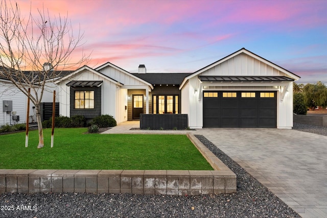 modern farmhouse style home featuring a standing seam roof, an attached garage, decorative driveway, a front lawn, and a chimney