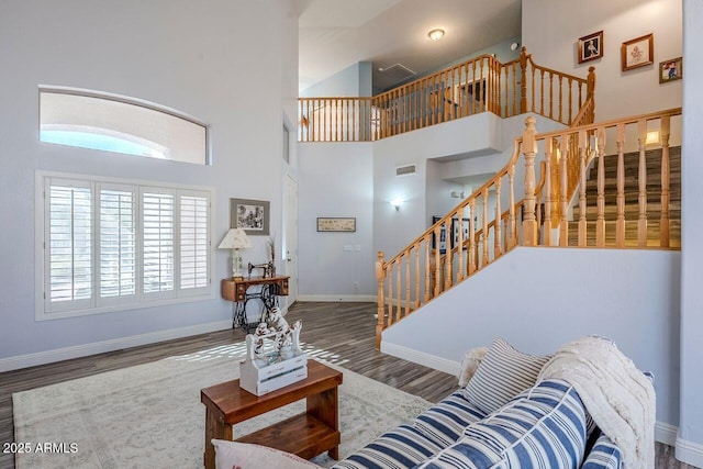 living room featuring a towering ceiling and hardwood / wood-style floors