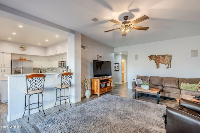 living room featuring wood-type flooring, ceiling fan, and vaulted ceiling