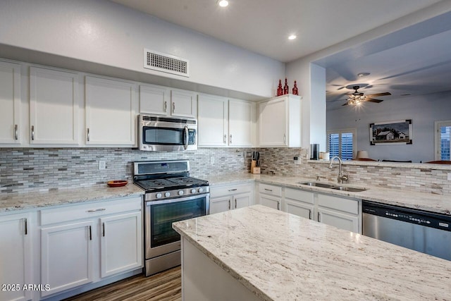 kitchen featuring light stone countertops, white cabinetry, stainless steel appliances, tasteful backsplash, and sink