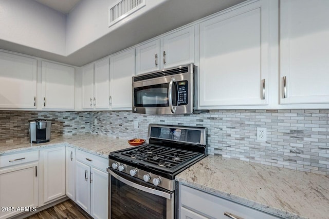 kitchen featuring decorative backsplash, light stone countertops, white cabinetry, and appliances with stainless steel finishes