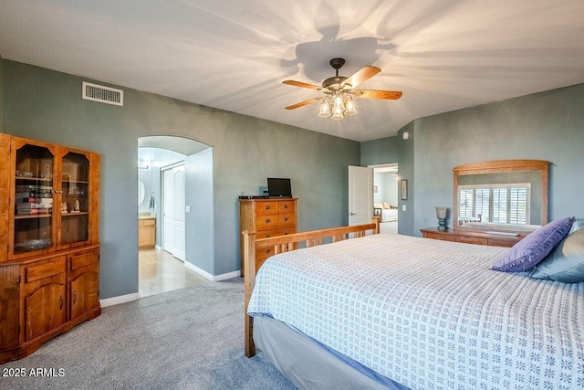 bedroom with light carpet, ensuite bathroom, and ceiling fan