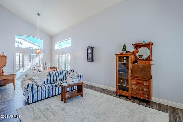 living room with an inviting chandelier, dark wood-type flooring, and high vaulted ceiling