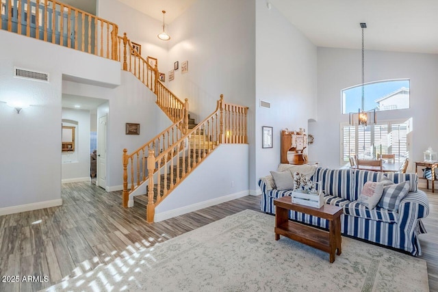 living room featuring an inviting chandelier, hardwood / wood-style floors, and high vaulted ceiling