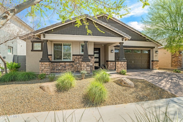 craftsman house featuring stucco siding, stone siding, a garage, and driveway