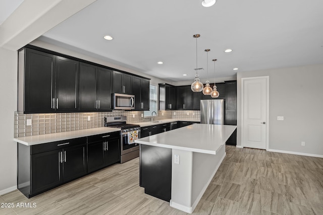 kitchen with a sink, stainless steel appliances, dark cabinetry, and light countertops