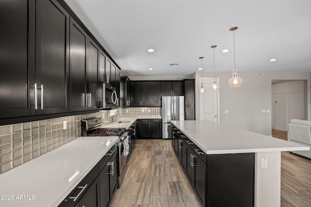 kitchen with dark cabinetry, a center island, tasteful backsplash, and stainless steel appliances