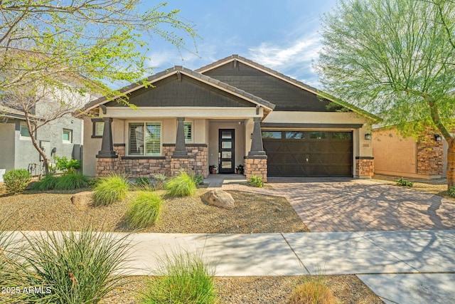 craftsman inspired home featuring decorative driveway, stone siding, a garage, and stucco siding