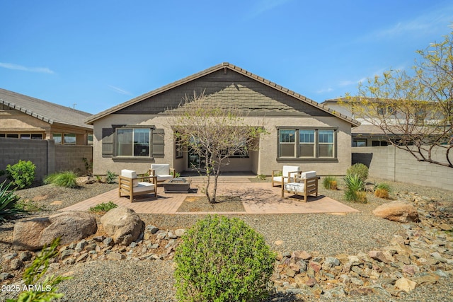 back of house with outdoor lounge area, a patio area, a fenced backyard, and stucco siding