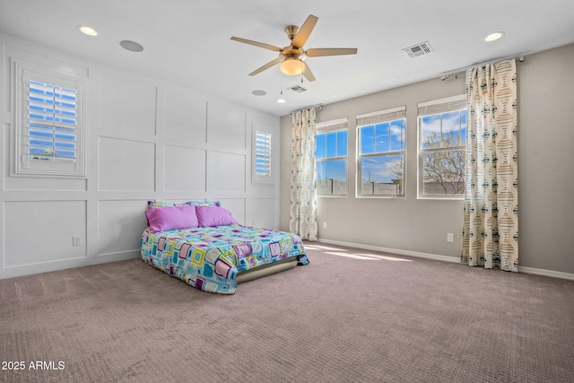 carpeted bedroom featuring a decorative wall, recessed lighting, baseboards, and visible vents