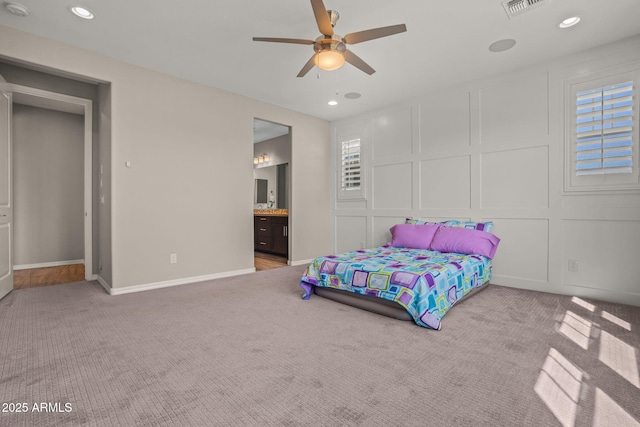 carpeted bedroom with recessed lighting, visible vents, ensuite bath, and a decorative wall