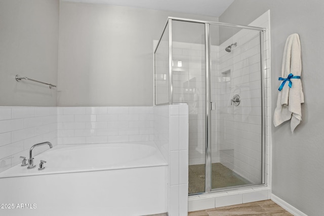 full bath with a shower stall, a bath, and wood finished floors