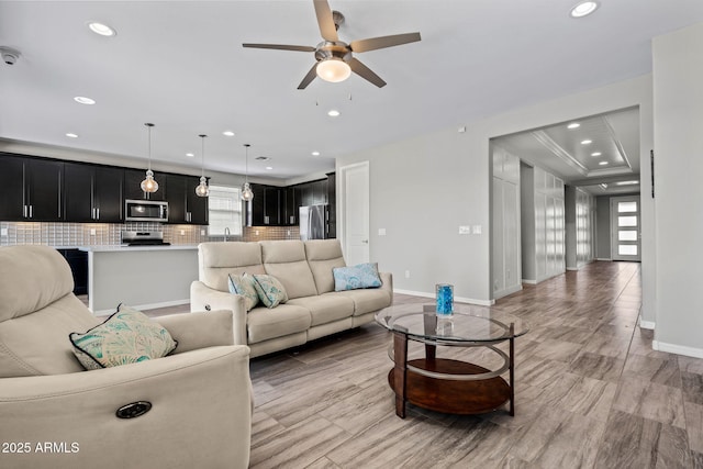 living room featuring recessed lighting, a ceiling fan, baseboards, and a wealth of natural light