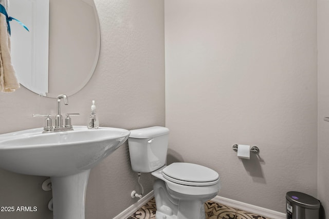 half bath with toilet, baseboards, and a textured wall