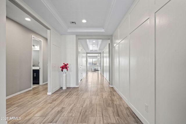 hallway with visible vents, recessed lighting, light wood-style floors, and a tray ceiling