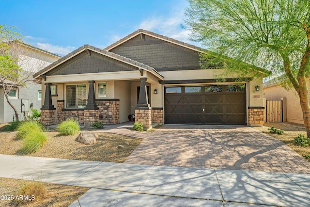 craftsman-style house with a garage, decorative driveway, stone siding, and stucco siding