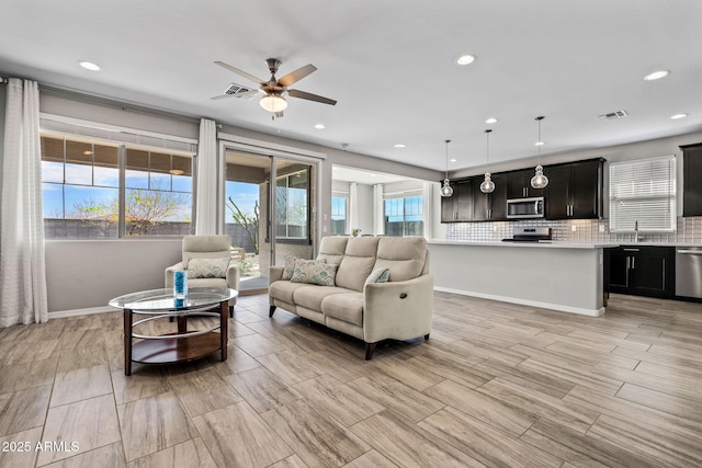 living area featuring visible vents, baseboards, and a ceiling fan