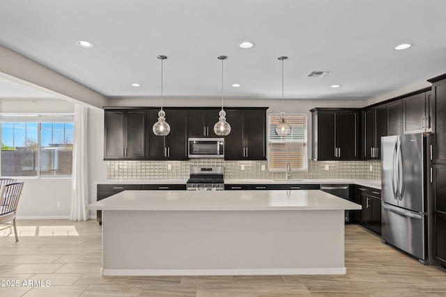 kitchen featuring visible vents, a sink, light countertops, appliances with stainless steel finishes, and a center island