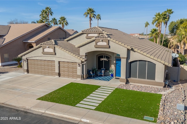 view of front facade with concrete driveway, an attached garage, a tiled roof, and stucco siding