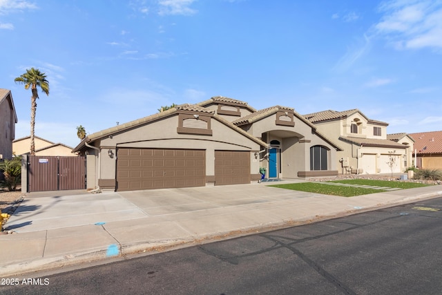 view of front of home featuring stucco siding, concrete driveway, a gate, a garage, and a tiled roof
