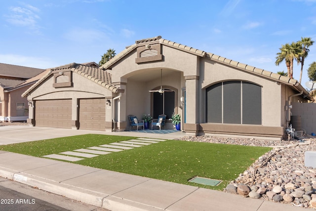 mediterranean / spanish house with a garage, concrete driveway, a tiled roof, a front lawn, and stucco siding