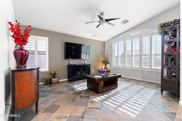 living room featuring lofted ceiling, baseboards, visible vents, and stone tile floors