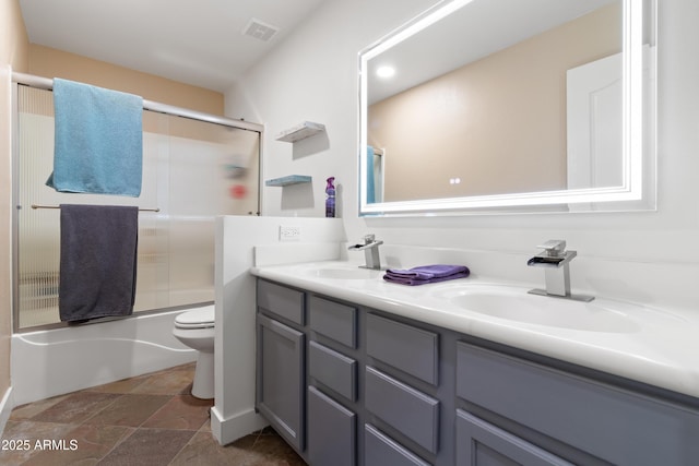full bath featuring toilet, double vanity, visible vents, and a sink