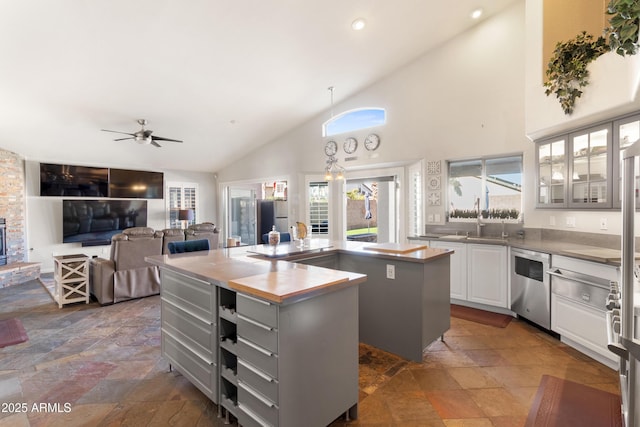 kitchen with stainless steel appliances, a kitchen island, white cabinets, and stone tile floors