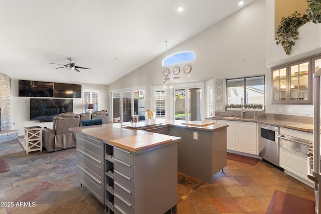 kitchen featuring a center island, stone tile floors, gray cabinets, glass insert cabinets, and dishwasher