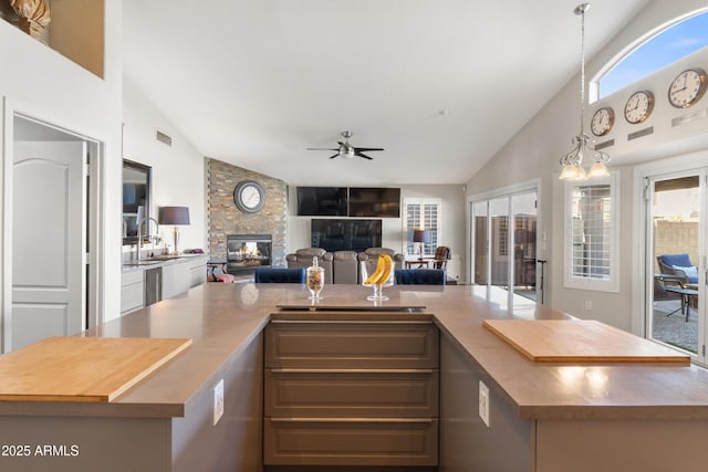kitchen featuring a ceiling fan, a large island, open floor plan, decorative light fixtures, and a fireplace