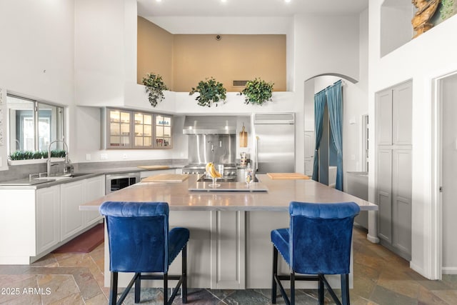 kitchen with a towering ceiling, wine cooler, a kitchen island, and stone tile flooring