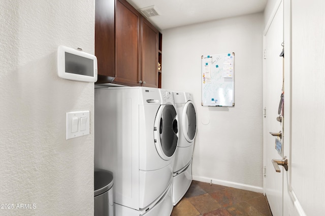 laundry room with visible vents, baseboards, independent washer and dryer, cabinet space, and stone finish flooring