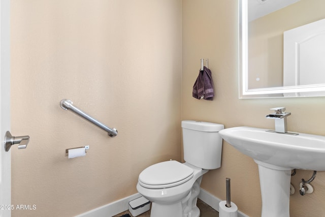 bathroom featuring baseboards and toilet