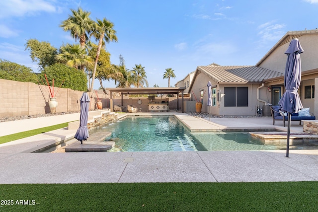 view of swimming pool featuring an in ground hot tub, an outdoor kitchen, a patio area, and a fenced backyard