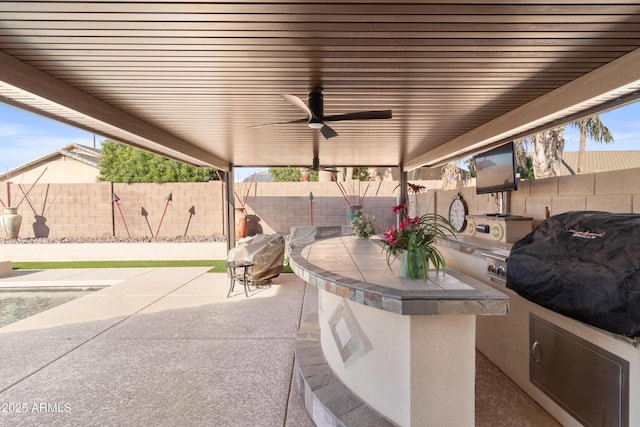 view of patio featuring area for grilling, a fenced backyard, ceiling fan, exterior kitchen, and outdoor dining space