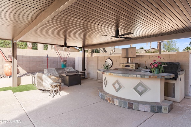 view of patio featuring a fenced backyard, an outdoor kitchen, a ceiling fan, and grilling area
