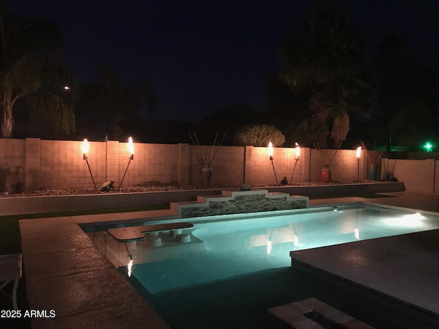 pool at night featuring a fenced backyard and a fenced in pool