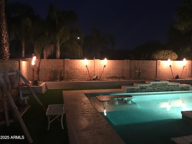 pool at night with a fenced in pool and a fenced backyard