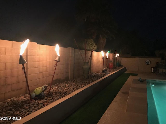pool at night featuring a fenced backyard and a fenced in pool