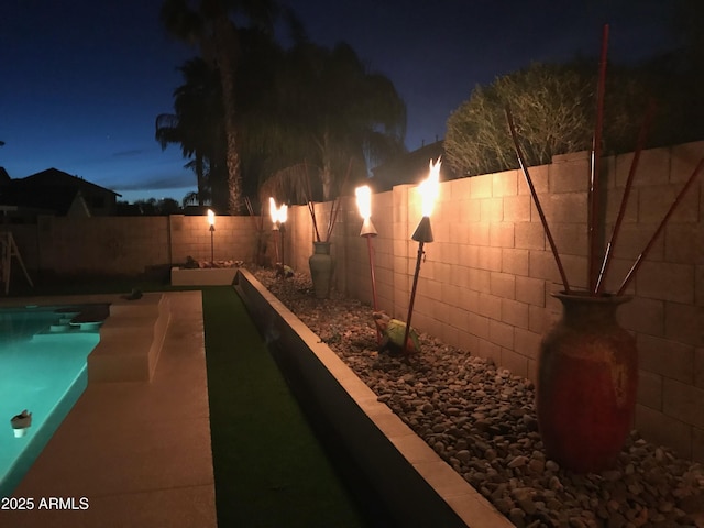 pool at night with a fenced in pool and a fenced backyard