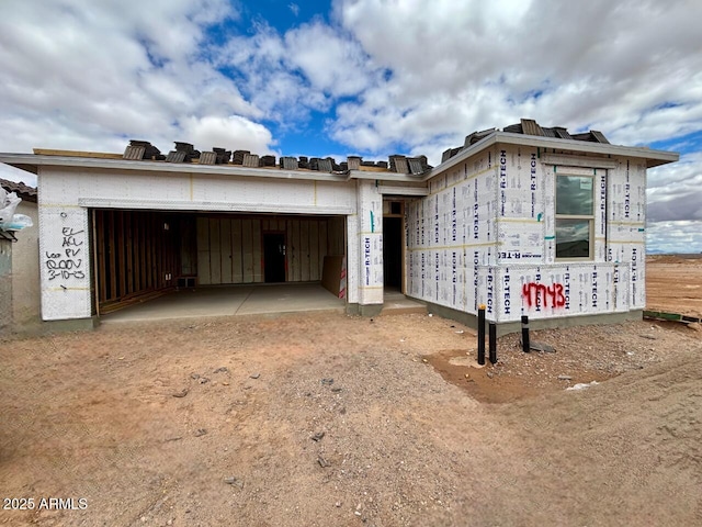 property in mid-construction with an attached garage and dirt driveway